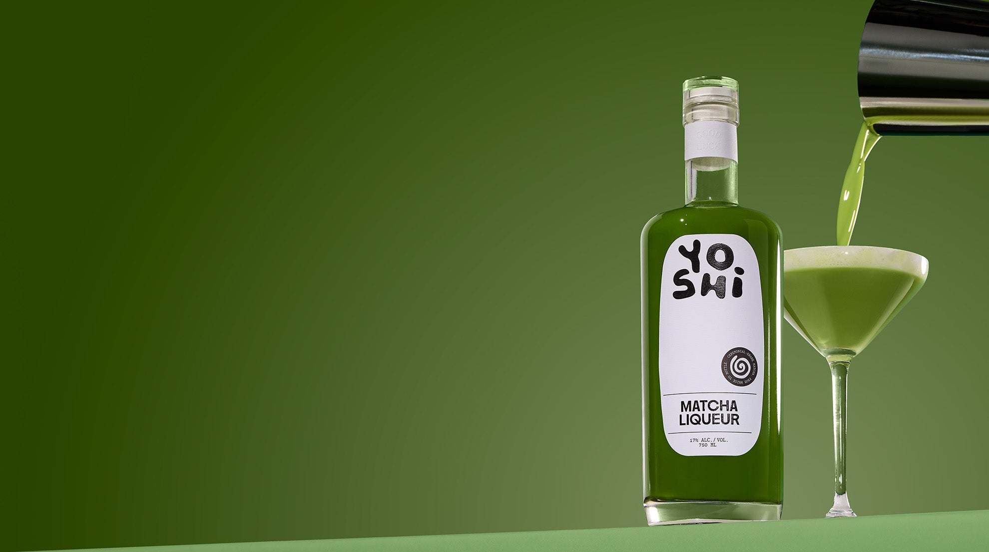 Bottle of Yoshi Matcha Liqueur with a glass being filled on a green background
